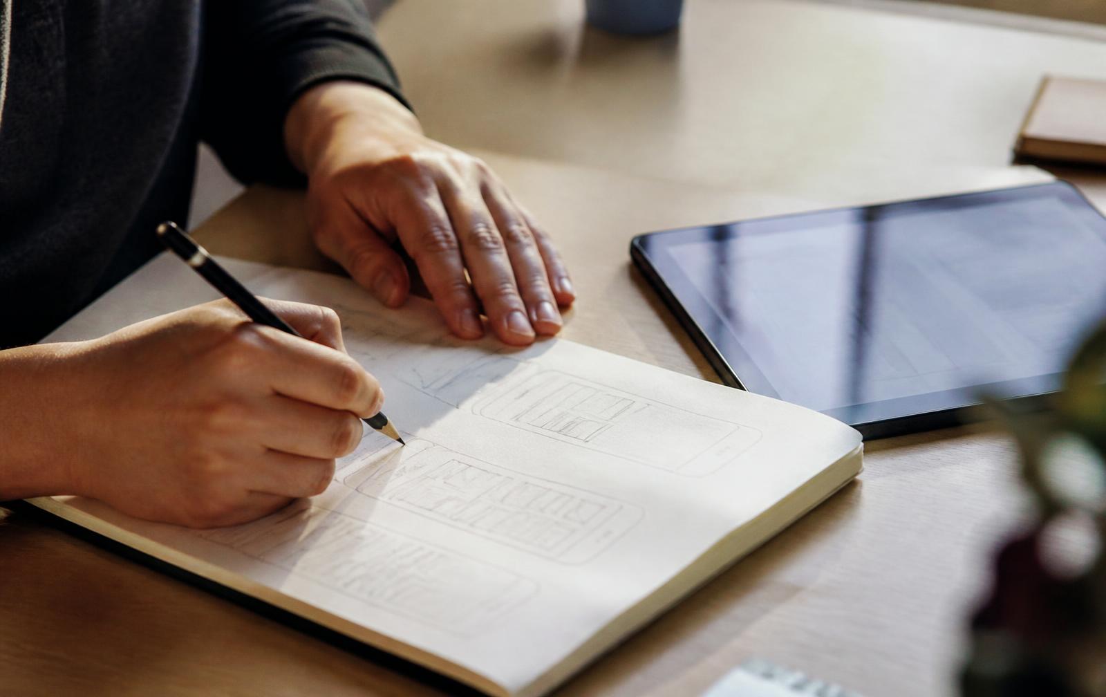 Designer sketching mobile app wireframes in a notebook