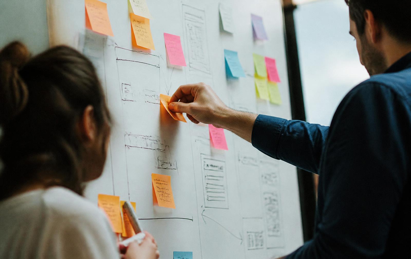 Team mapping user flows with sticky notes on a whiteboard